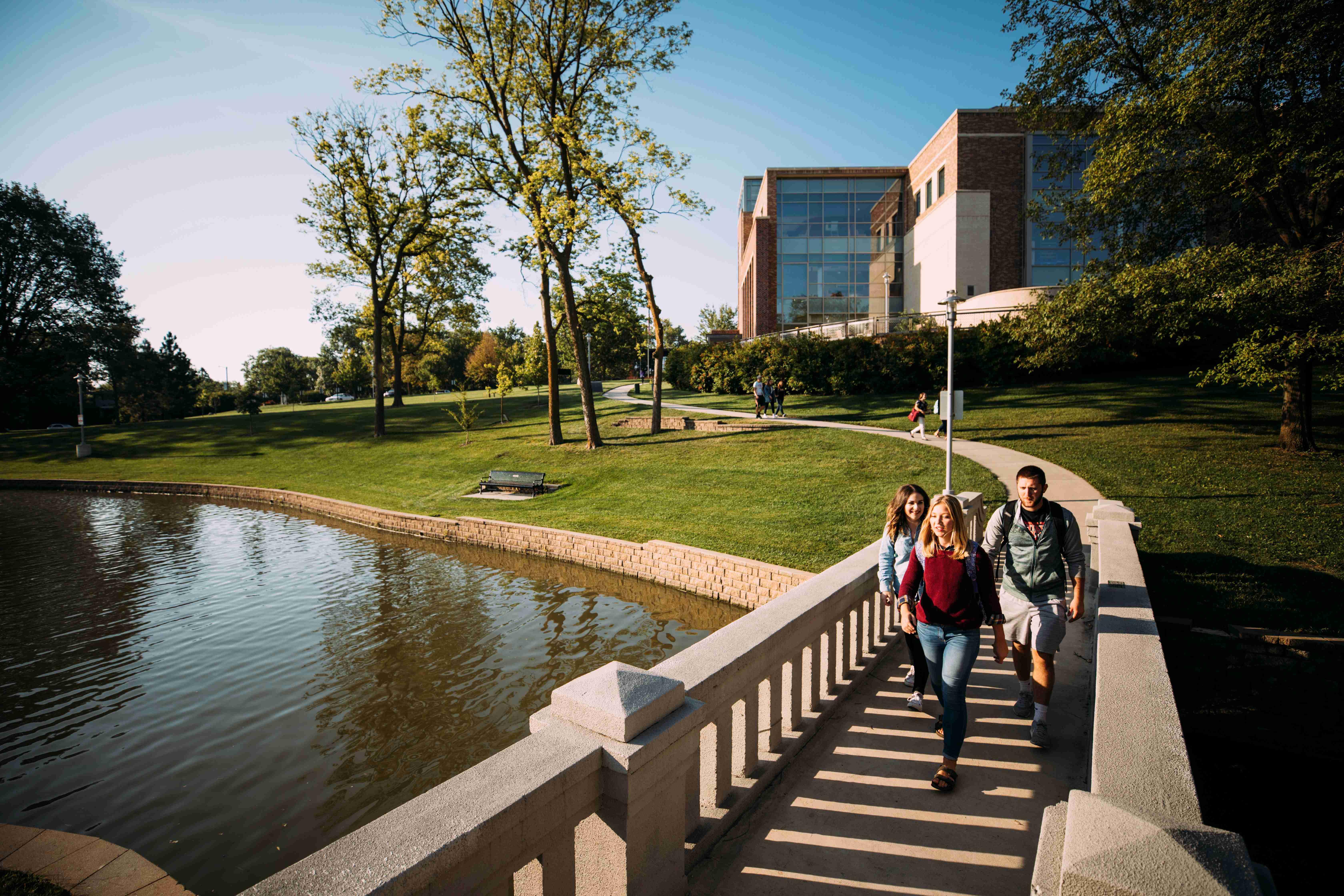 Students walking over lake bridge